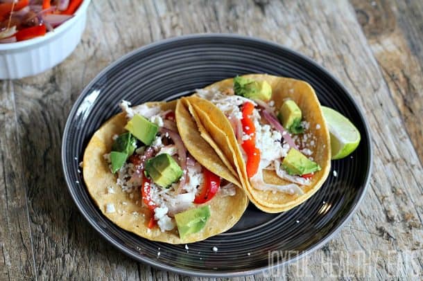 Close up of two Chicken Tacos with cheese and avocado on top