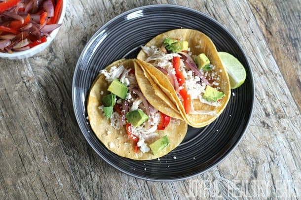 Two shredded Rotisserie Chicken Tacos on a black plate