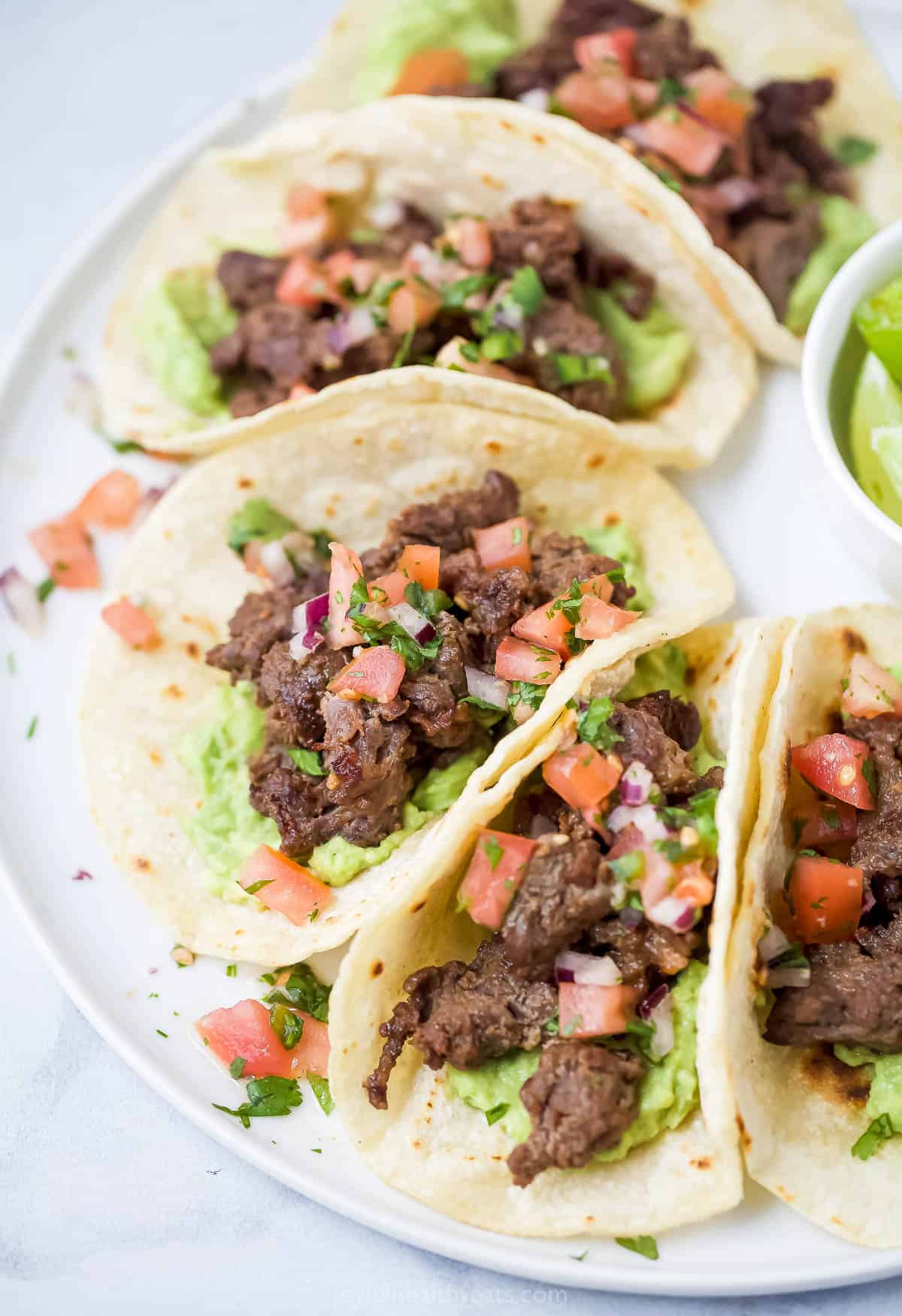 Angled photo of steak tacos with veggie toppings. 