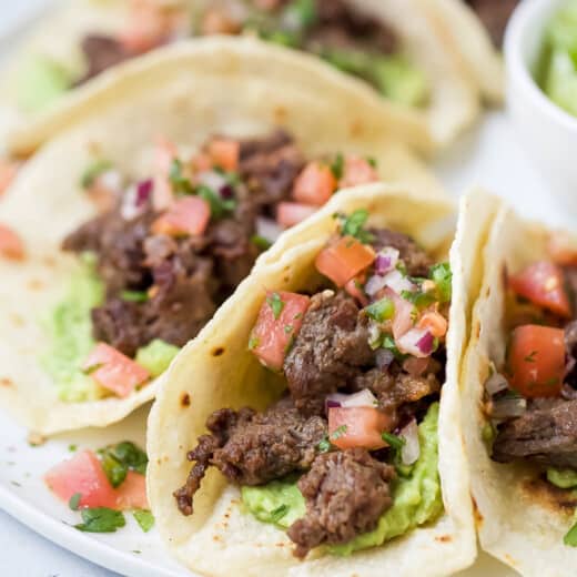 Close-up of skirt steak tacos with veggie toppings.