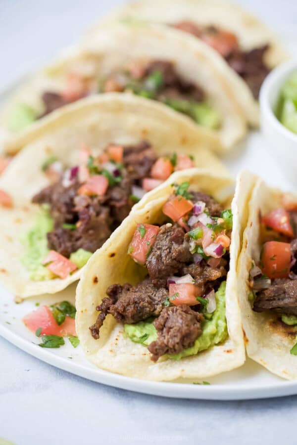 Close-up of skirt steak tacos with veggie toppings.