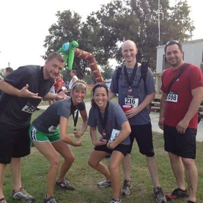 A group of 5 runners with race bibs and medals