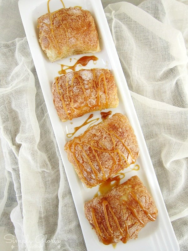 Four caramel pumpkin empanadas made with puff pastry on a white rectangular plate