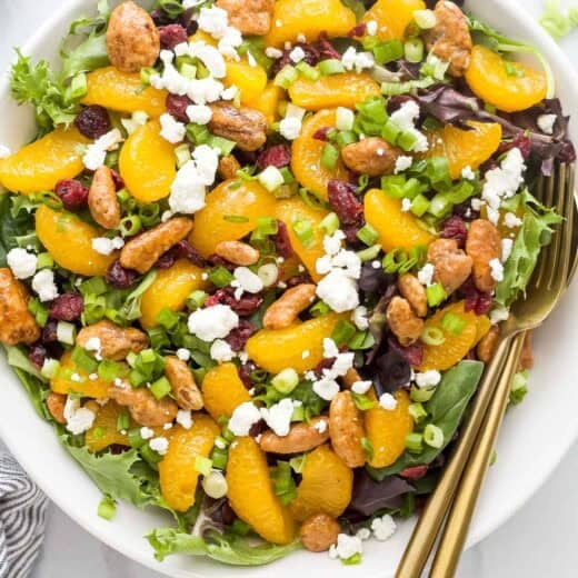 Bowl of cranberry mandarin orange salad with fork and spoon.