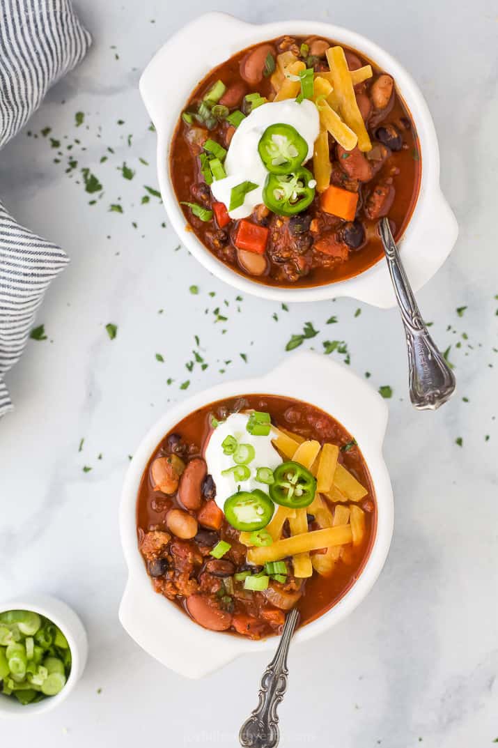 Two bowls filled with crock pot chili and toppings.