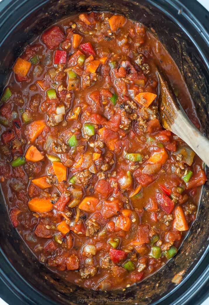 Three bean chili in a crock pot with a wooden spoon.