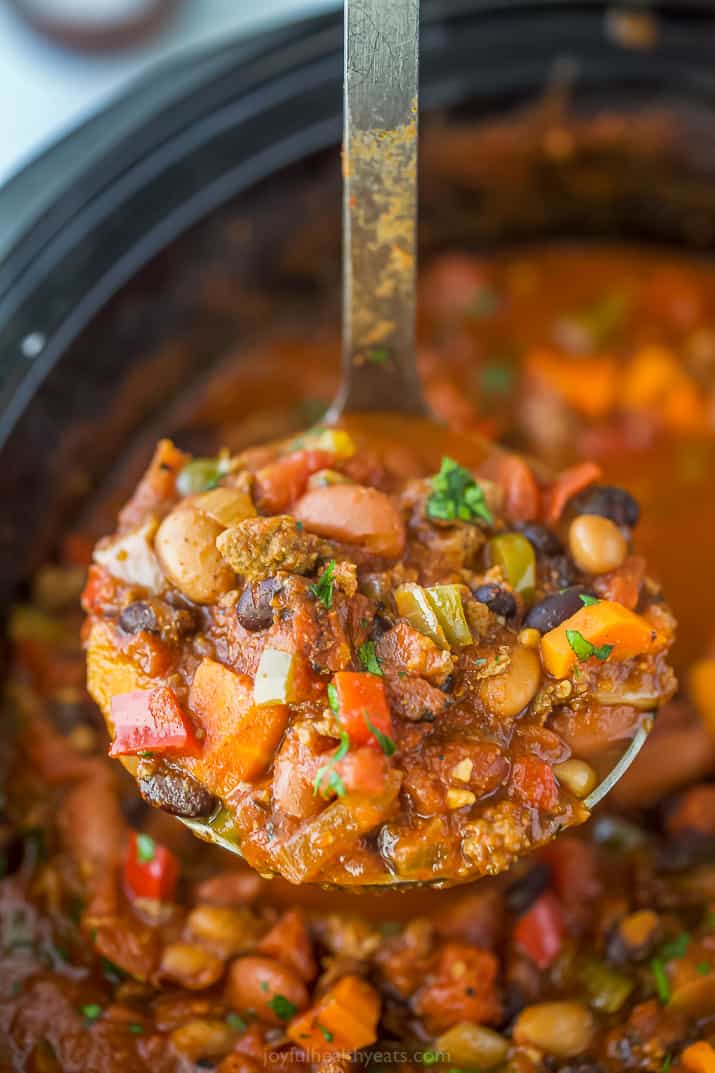 Ladle scooping chili from a crock pot.