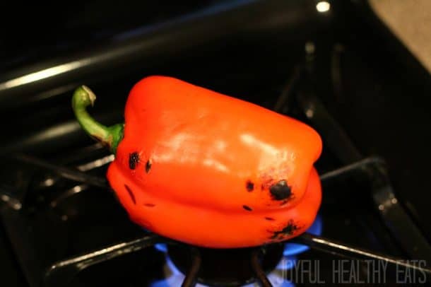 A red pepper being roasted over fire