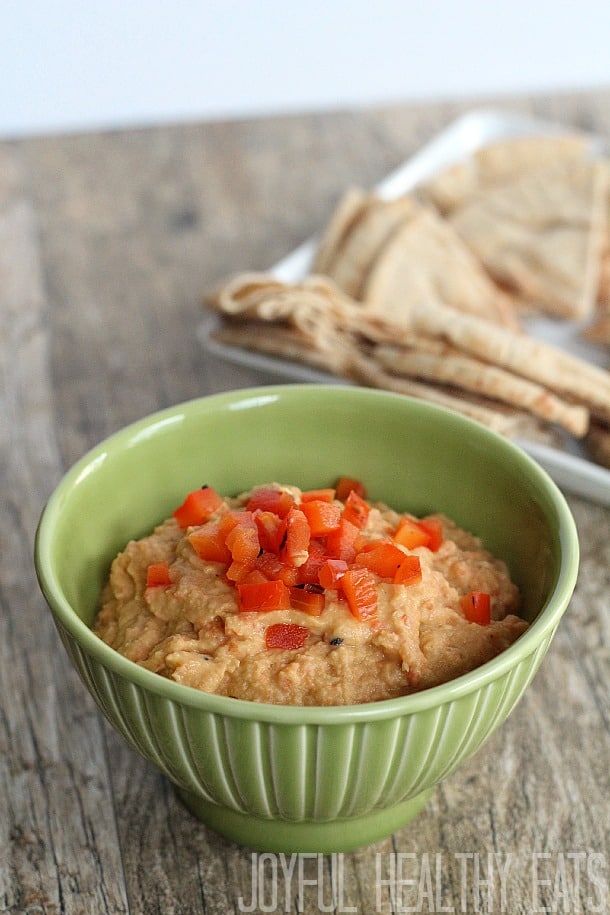 A green bowl of red pepper hummus