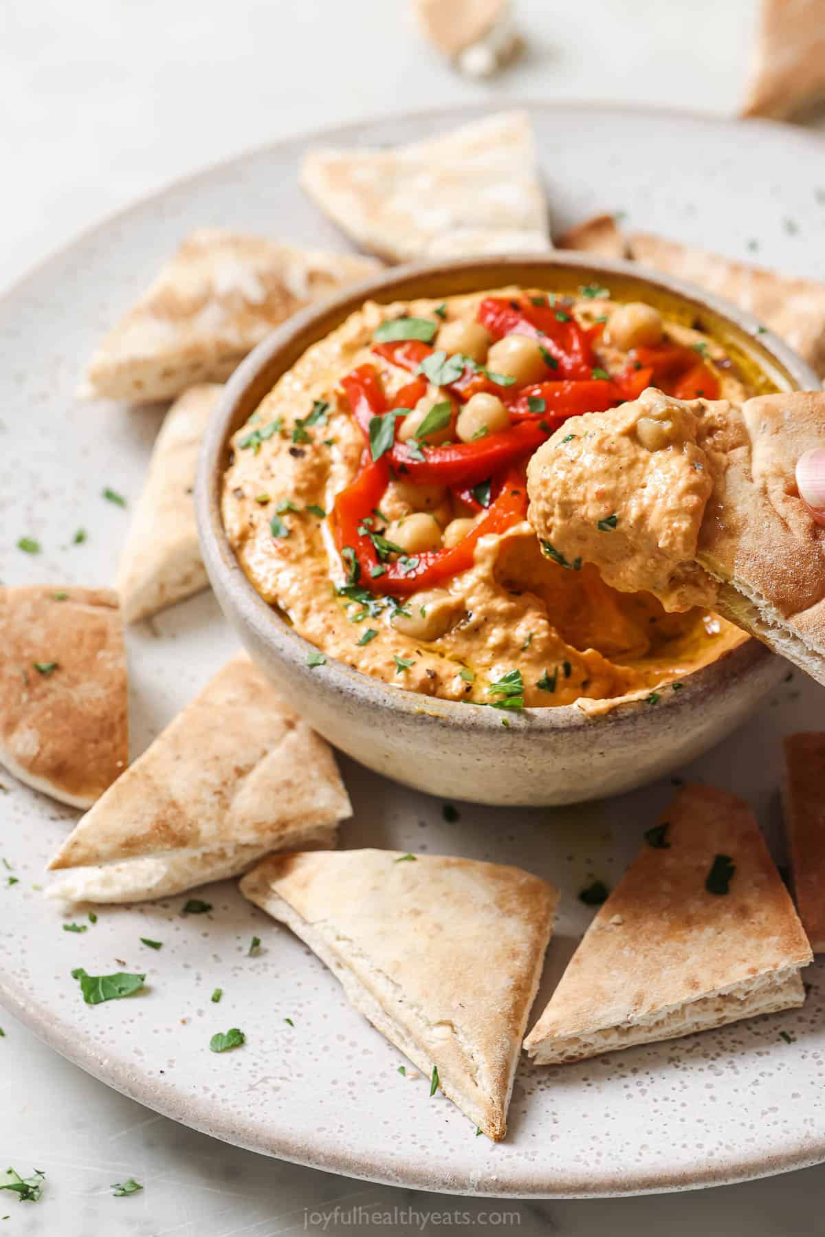 Dipping a pita chip into the chickpea dip. 