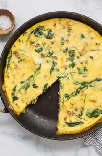 Potato frittata in the skillet with a missing slice.