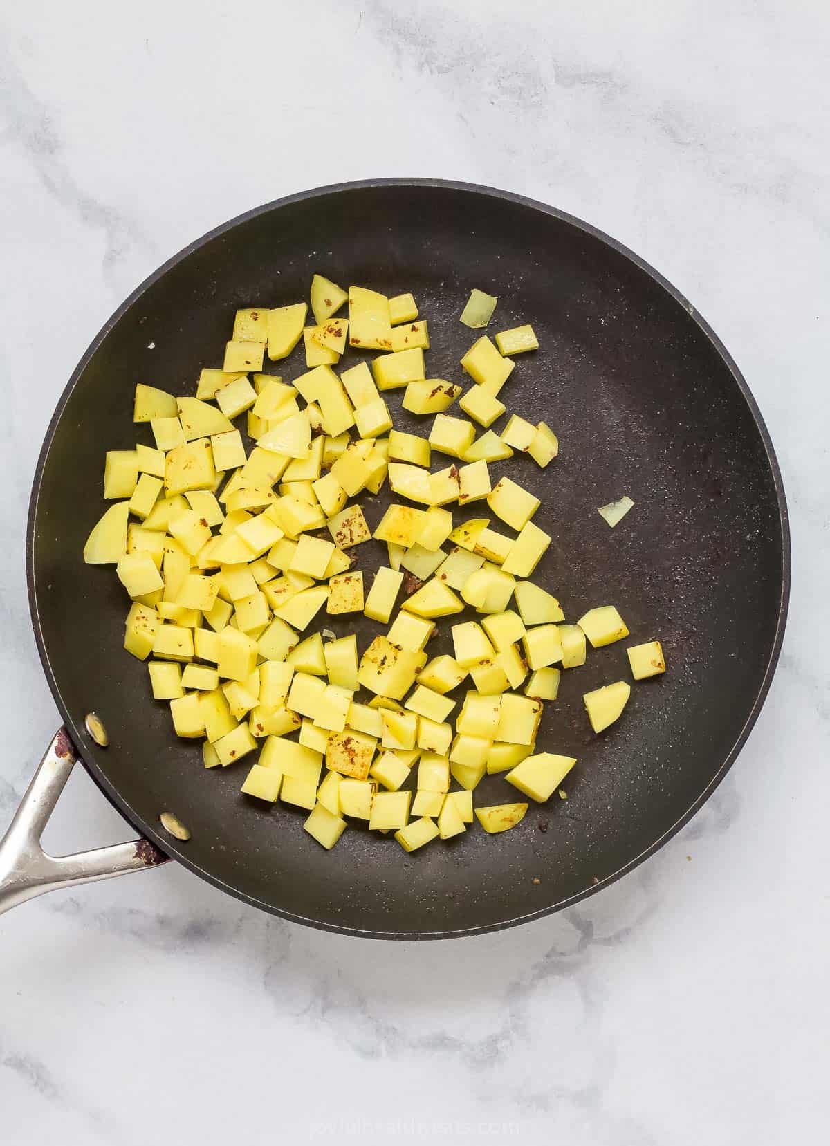 Adding the diced potatoes to the skillet. 