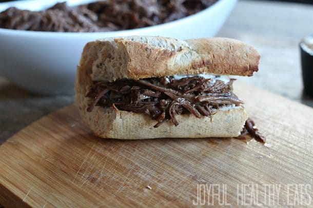 A toasted sandwich bun with shredded beef and horseradish aioli