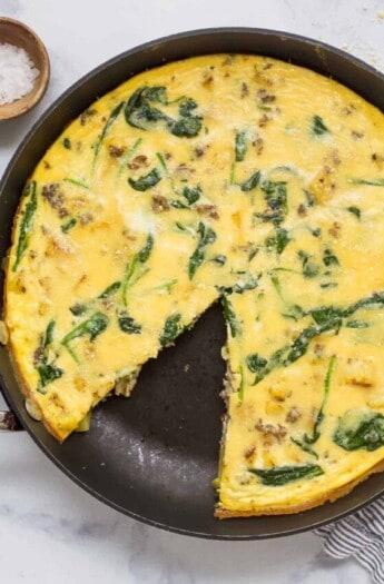 Potato frittata in the skillet with a missing slice.
