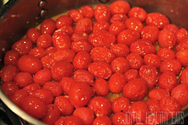 Burst grape tomatoes cooking in a skillet