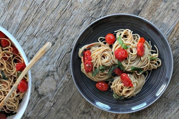 Spaghetti with burst grape tomatoes and basil in a pasta bowl