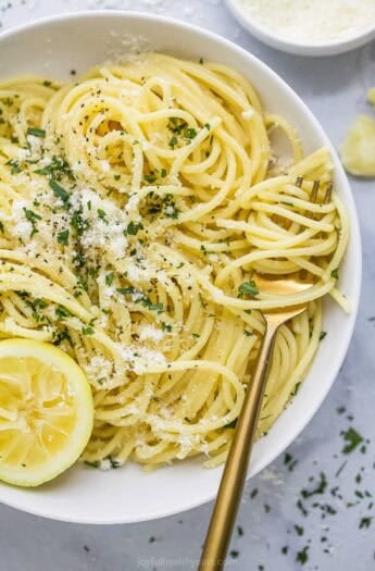 Lemon garlic pasta twirled around fork set in bowl