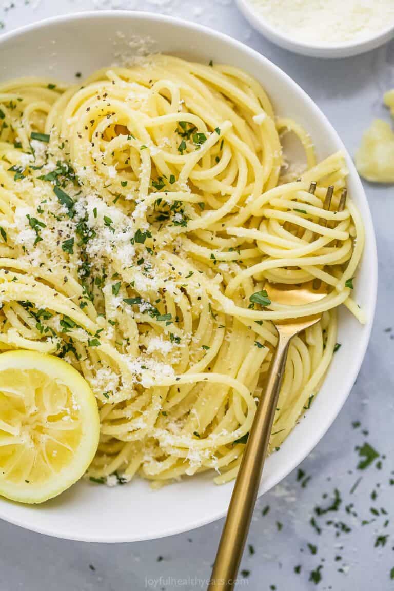 Lemon garlic pasta twirled around fork set in bowl