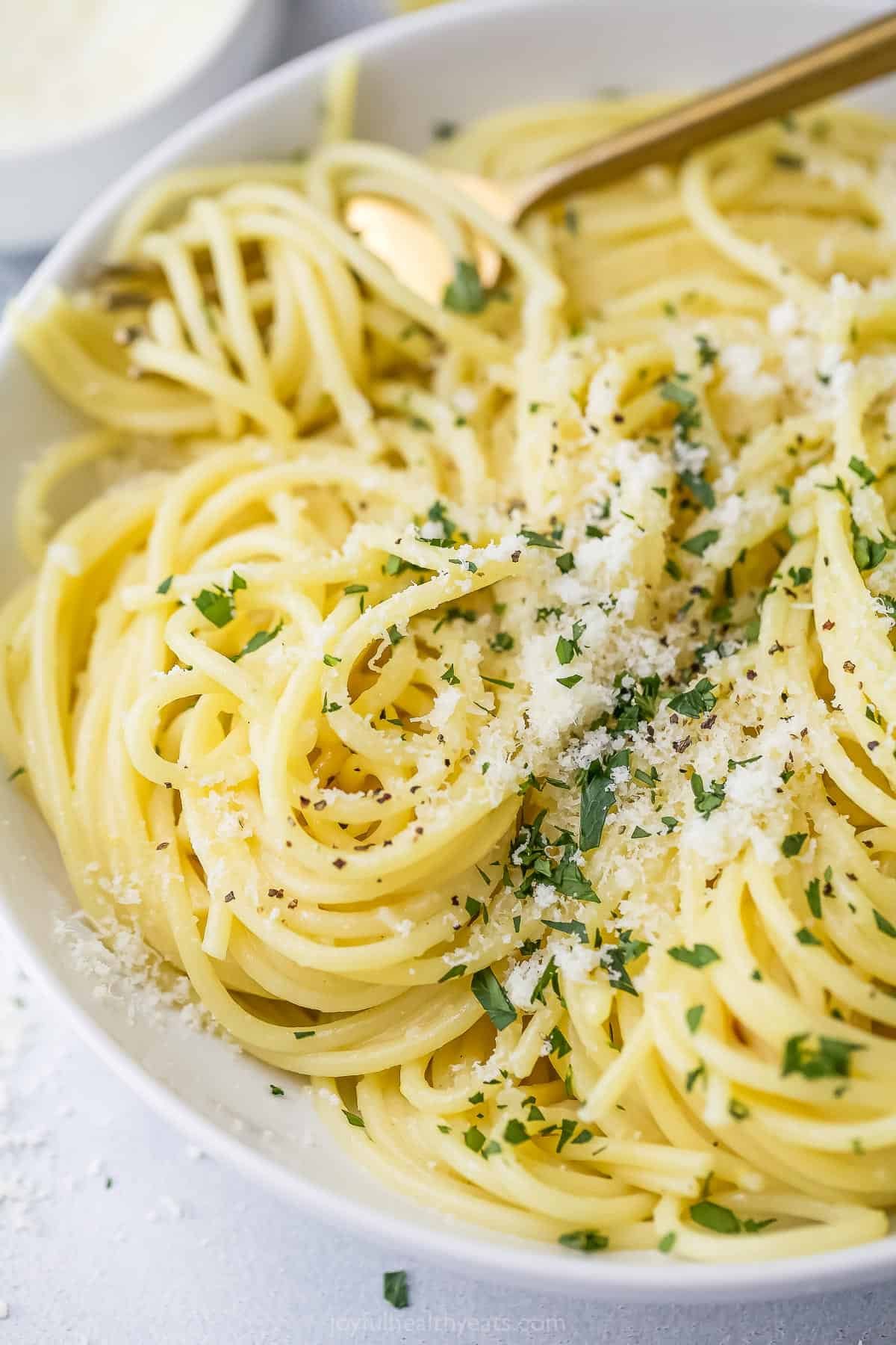 This Lemon Garlic Pasta is a 15-minute dinner elevated enough for a date night, but it's made with a short and simple list of ingredients! Bowl of creamy lemon garlic pasta with minced parsley and Parmesan