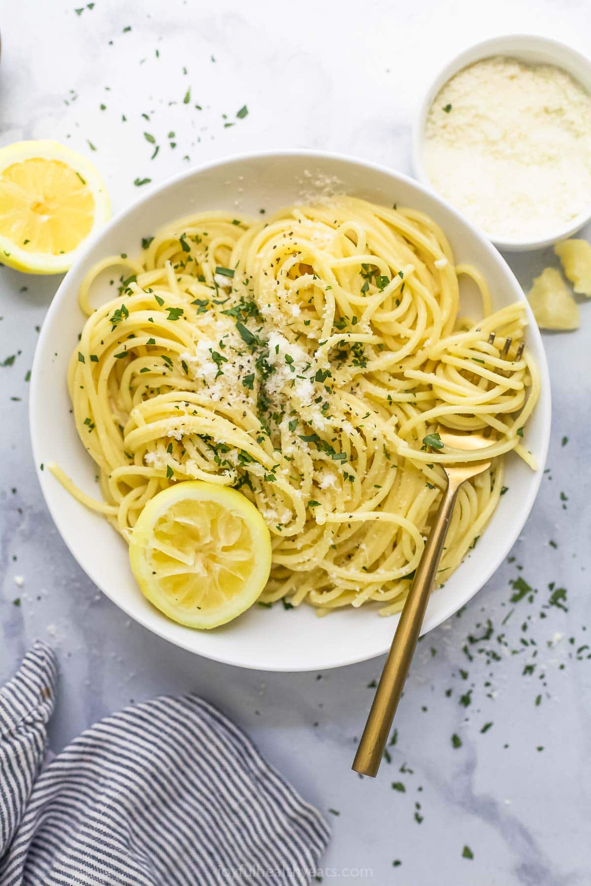 This Lemon Garlic Pasta is a 15-minute dinner elevated enough for a date night, but it's made with a short and simple list of ingredients! Overhead view of lemon garlic pasta in bowl with Parmesan and parsley