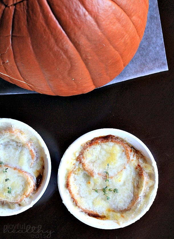 Top view of two ramekins of French Onion Soup next to a pumpkin