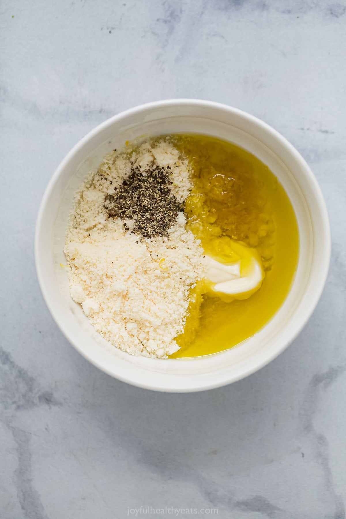 Ingredients for homemade Caesar dressing in bowl before whisking.
