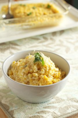 A bowl of creamy corn topped with parmesan and fresh herbs