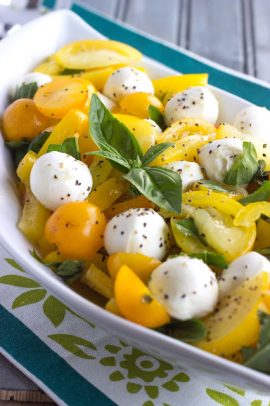 A bowl of lemon caprese salad with mozzarella balls and yellow cherry tomatoes