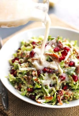 A bowl of chopped brussels sprout salad with cranberries and creamy dressing