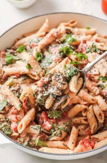 Grabbing some creamy spinach mushroom pasta with a fork.