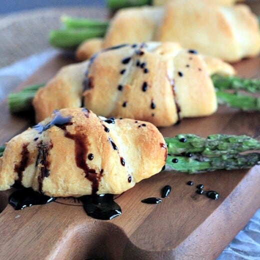 Four Asparagus Rollups on a Wooden Cutting Board