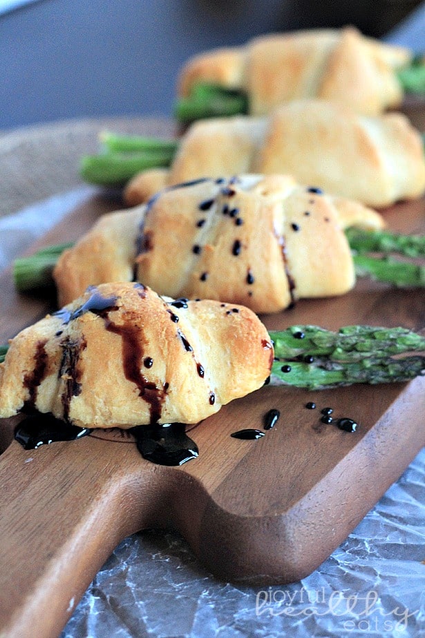 Four Asparagus Rollups on a Wooden Cutting Board