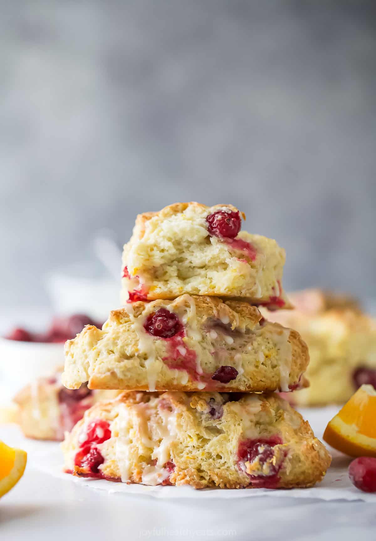 Three stacked cranberry orange scones with orange glaze. 