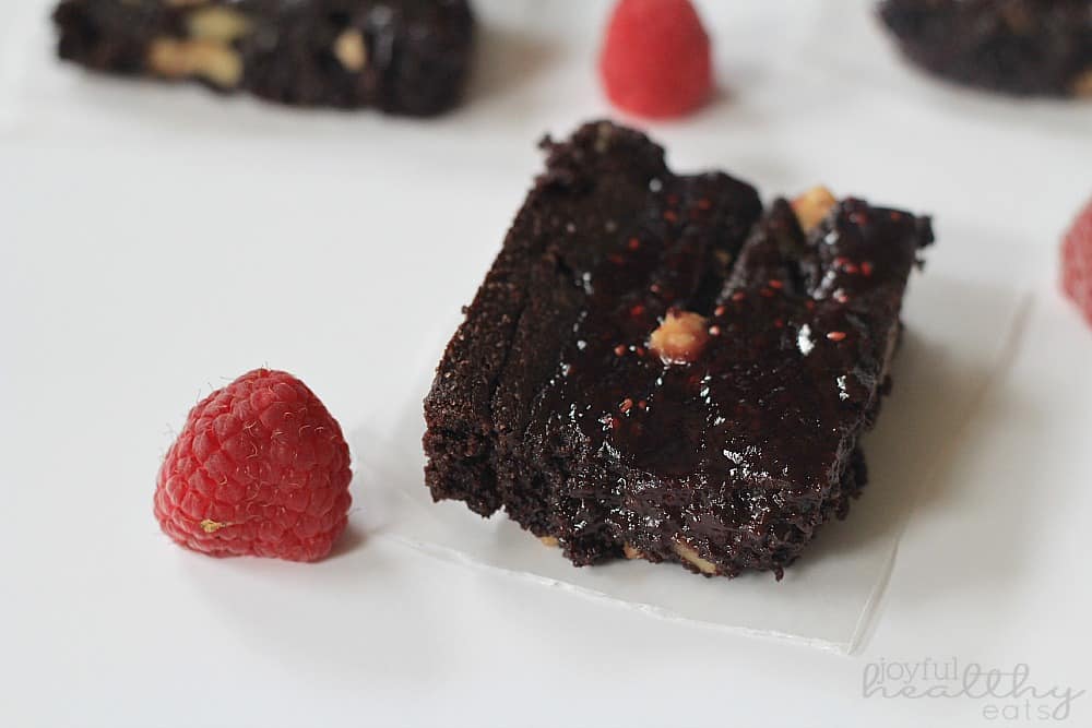 Dark Chocolate Raspberry Swirl Brownie on a square of parchment next to fresh raspberries