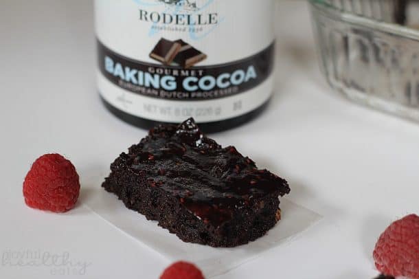 Dark Chocolate Raspberry Swirl Brownie next to a can of baking cocoa and fresh raspberries