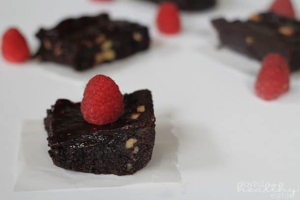 Dark Chocolate Raspberry Swirl Brownie on a square of parchment with fresh raspberries