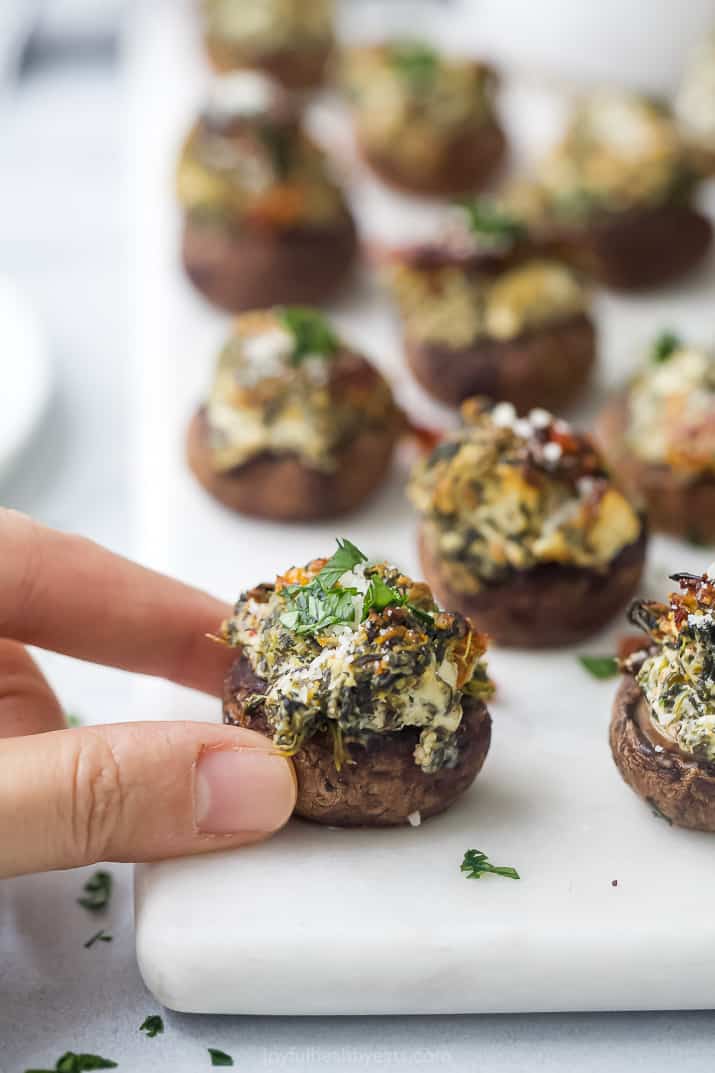 hands holding a spinach stuffed mushroom