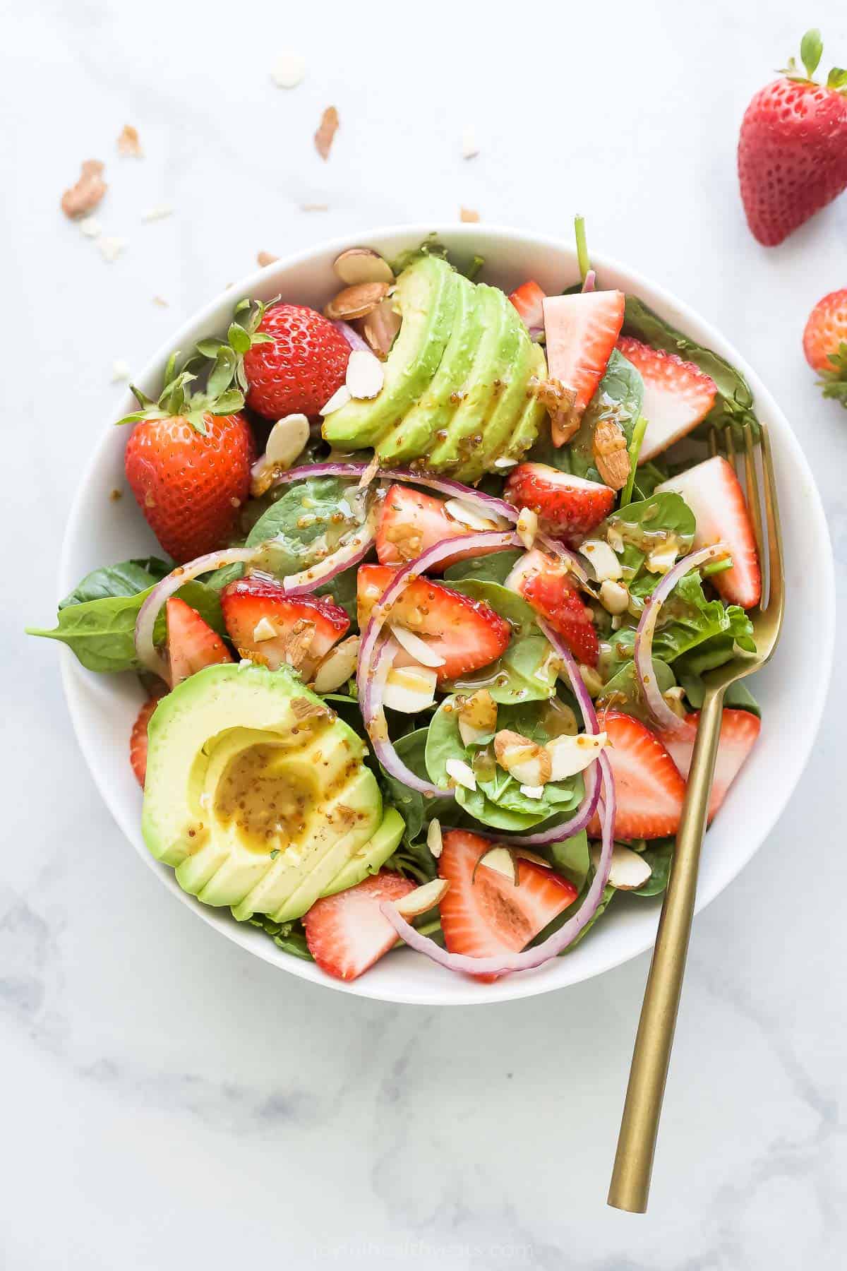 Bowl of salad with lots of strawberries and avocado. 