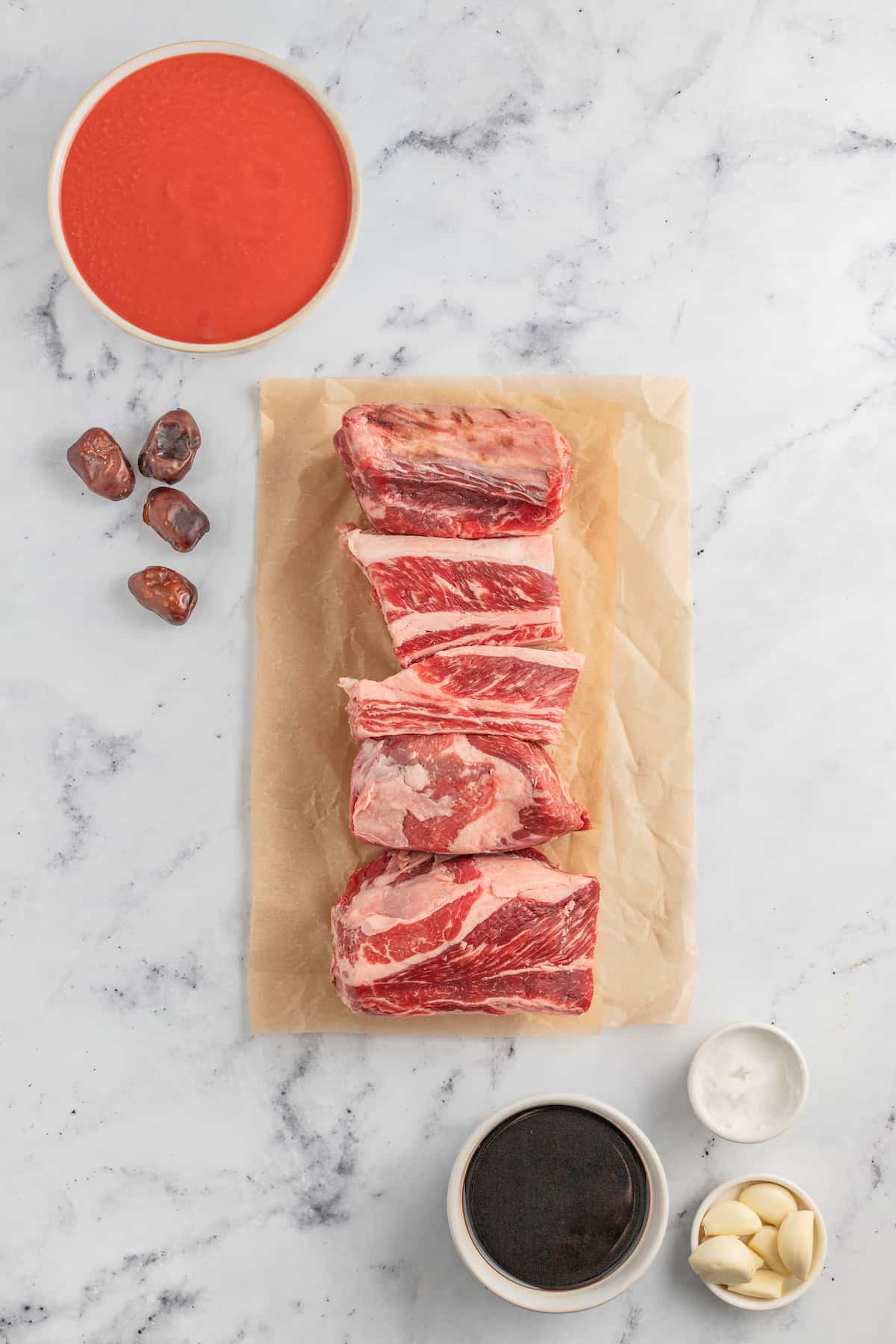 beef short ribs on parchment paper on a marble countertop