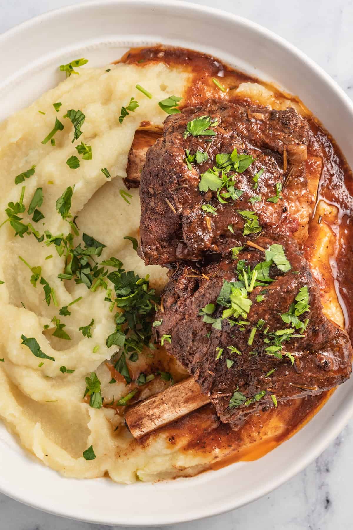 Slow Cooker Balsamic Braised Beef Short Ribs are a hearty Paleo recipe. Made with juicy beef short ribs & balsamic vinegar, simple yet fancy! brasied balsamic short ribs plated with pureed potatoes and garnished with herbs