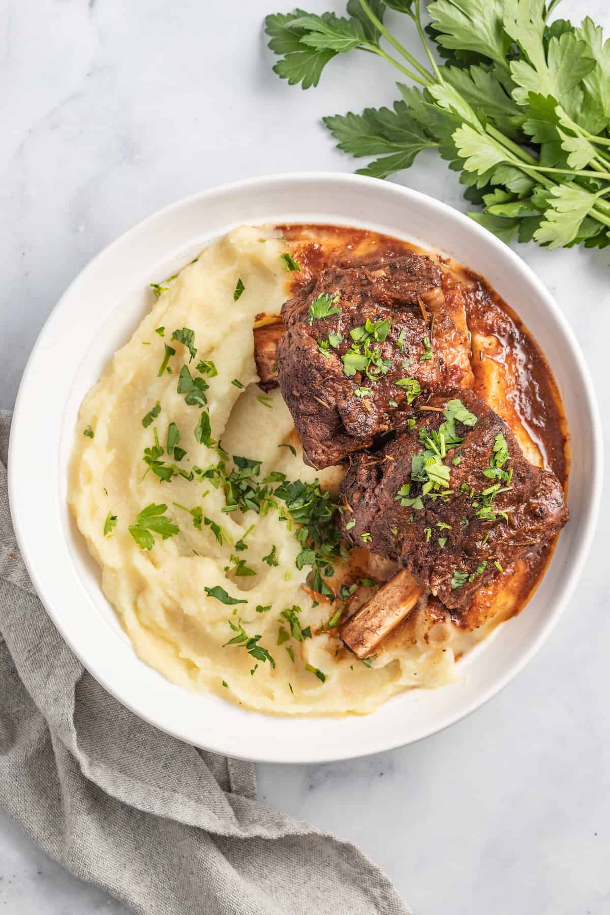 brasied balsamic short ribs plated with pureed potatoes and garnished with herbs