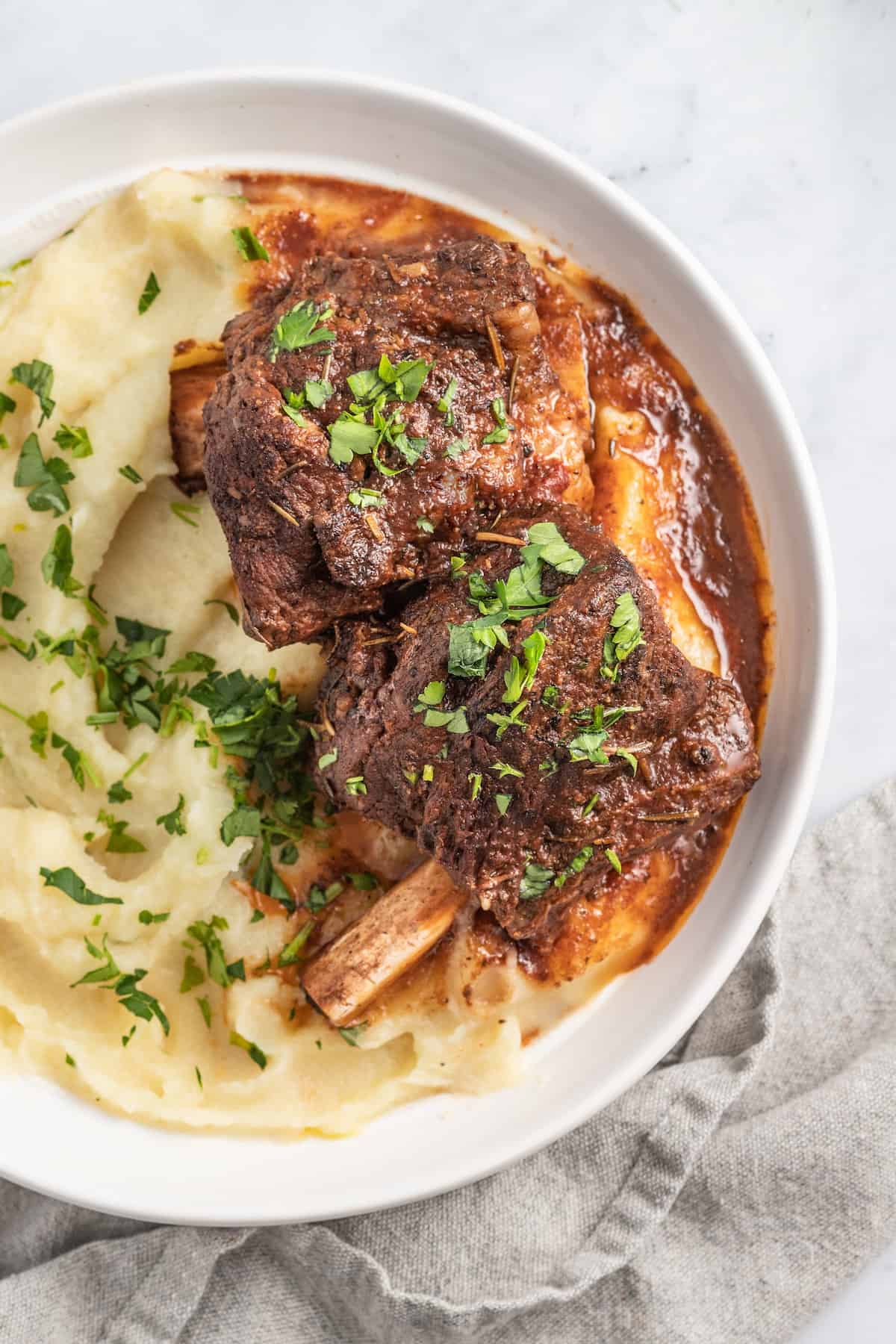 brasied balsamic short ribs plated with pureed potatoes and garnished with herbs