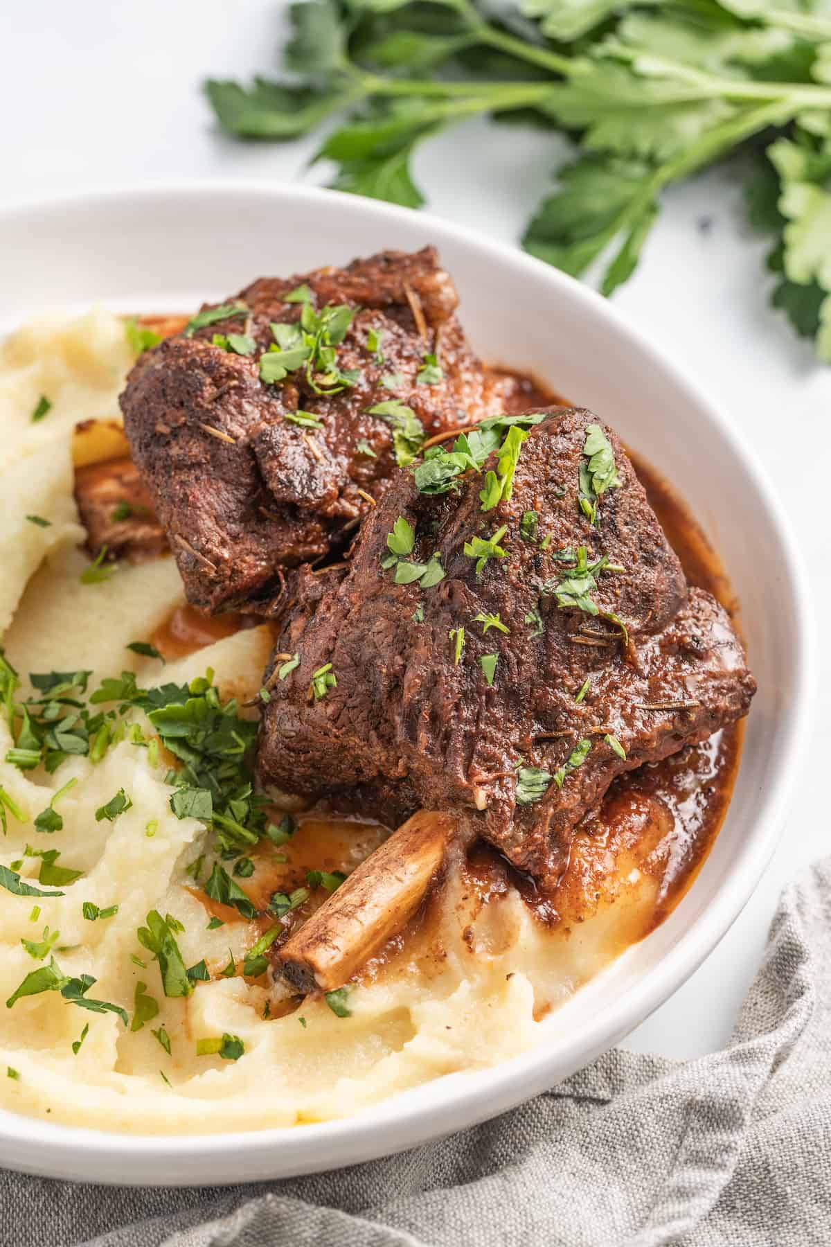 brasied balsamic short ribs plated with pureed potatoes and garnished with herbs