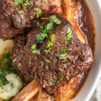 brasied balsamic short ribs plated with pureed potatoes and garnished with herbs
