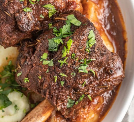 brasied balsamic short ribs plated with pureed potatoes and garnished with herbs