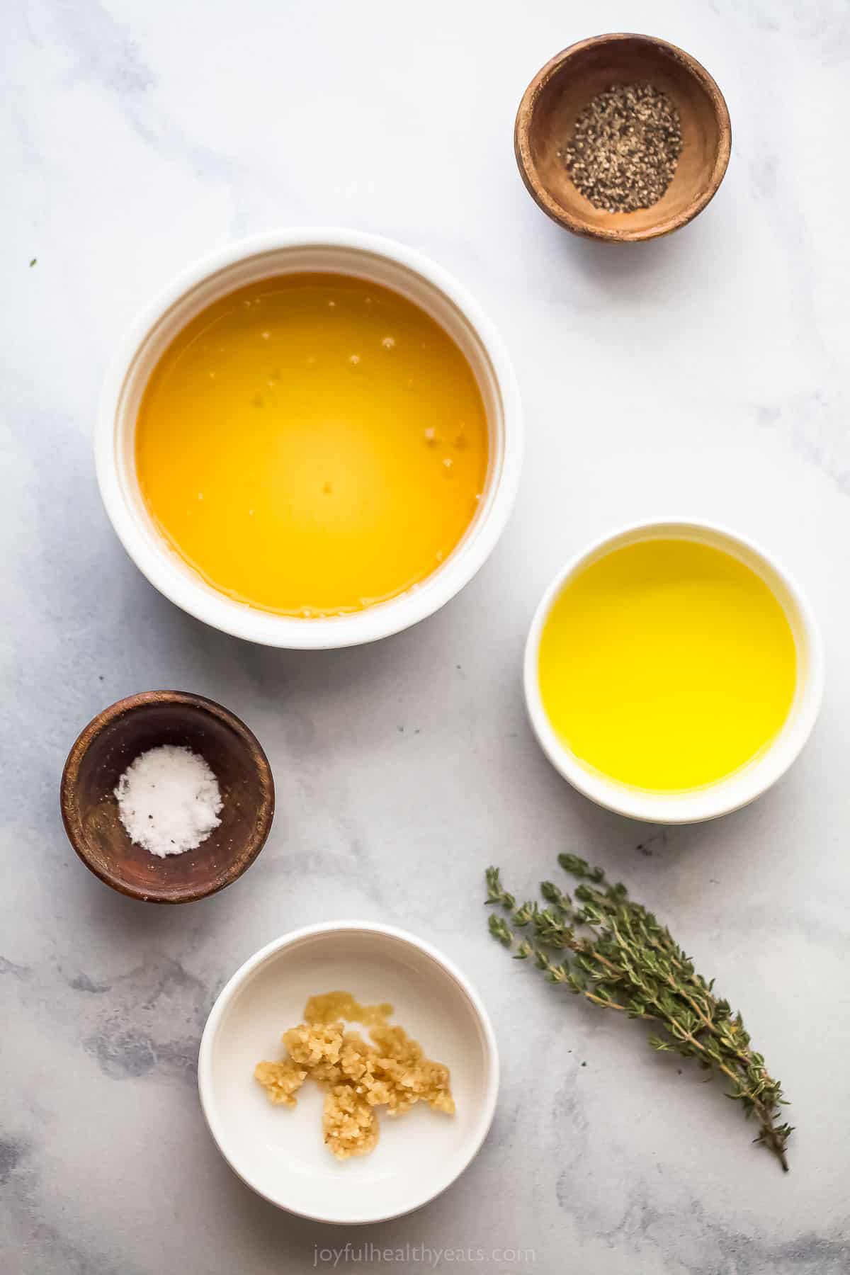 small bowls with olive oil, honey, salt, and freshthyme on the table