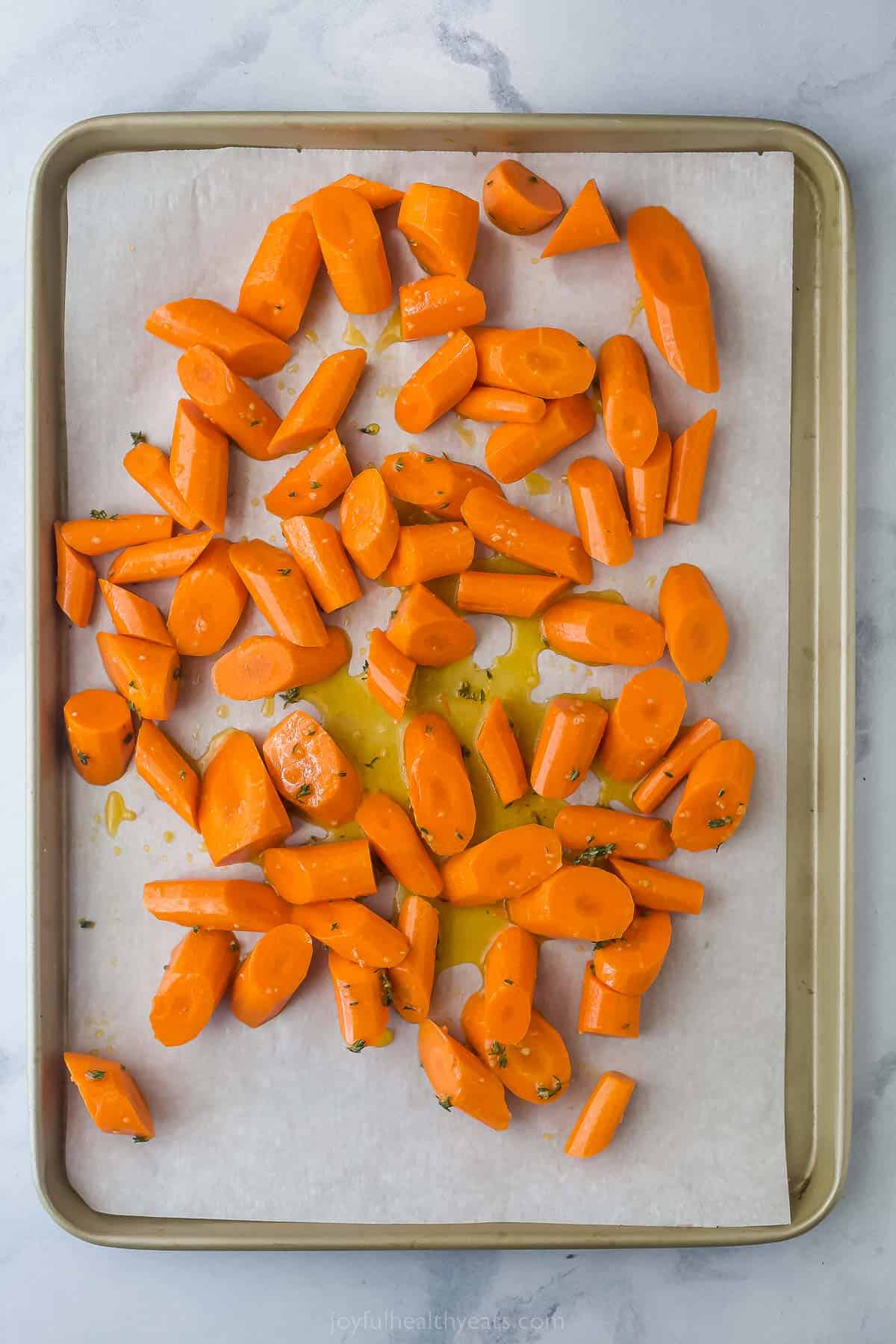 raw carrots tossed in spices and honey on a sheet tray