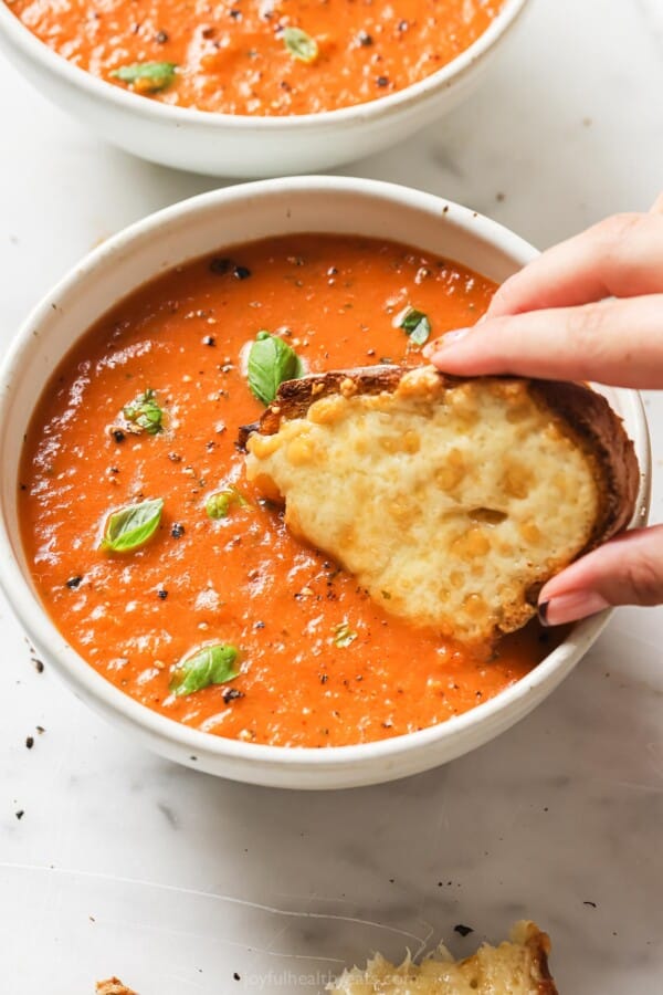 Dipping a slice of bread with melted cheese into the soup.