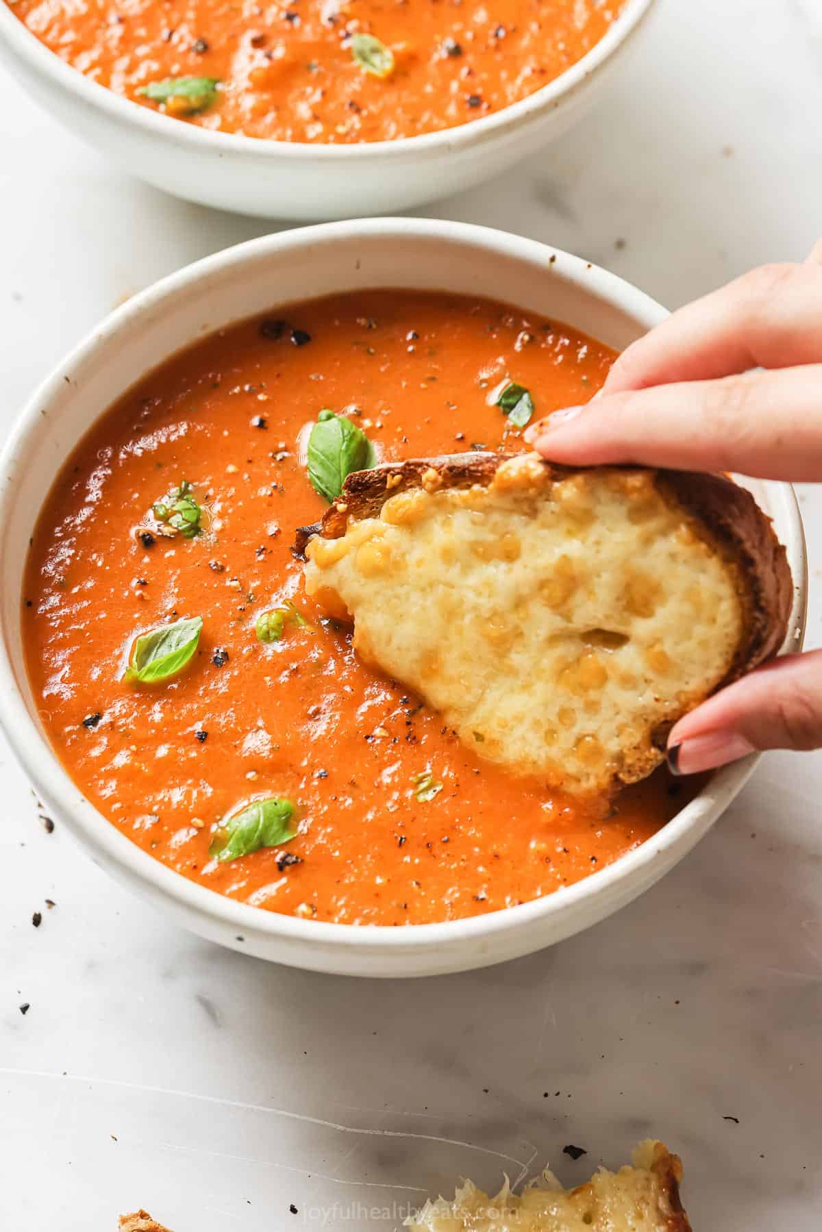 Dipping a slice of bread with melted cheese into the soup. 