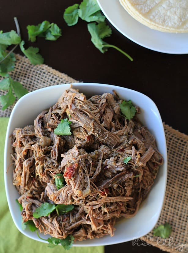 A plate of slow cooker chipotle barbacoa topped with fresh chopped herbs